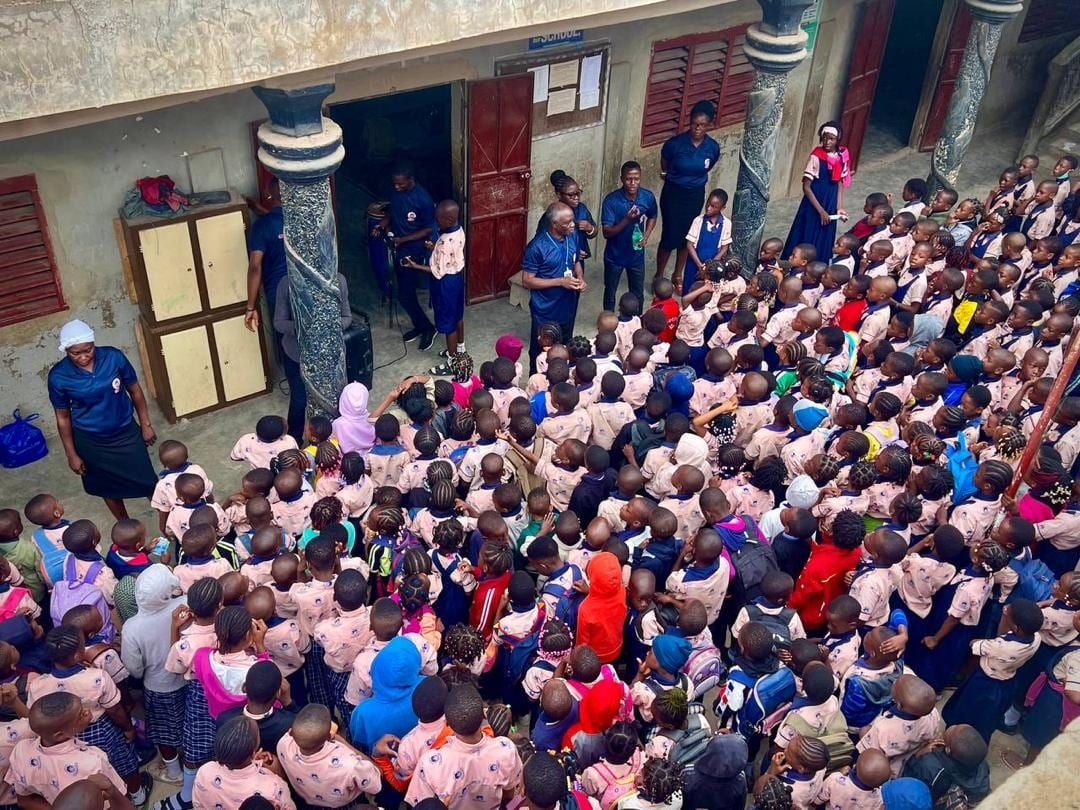 Des élèves rassemblés dans la cour de l’école pour l’assemblée du matin, face au personnel en polo bleu marine.